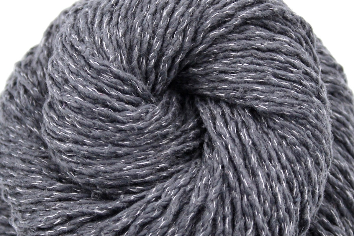 A close up shot of a skein of Grey Yarn recycled by hand from unwanted sweaters beautifully coiled in the center of the frame