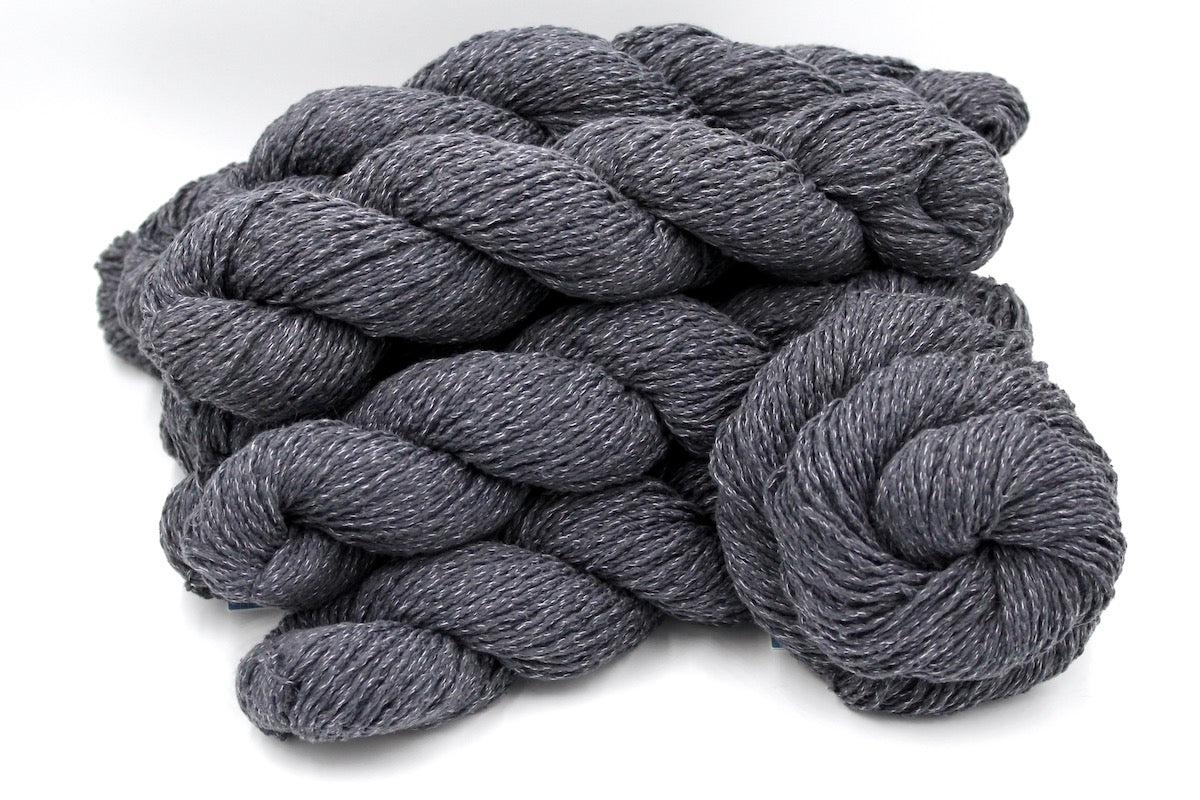 Several skeins of Grey recycled by hand from unwanted sweaters stacked on top of each other attractively