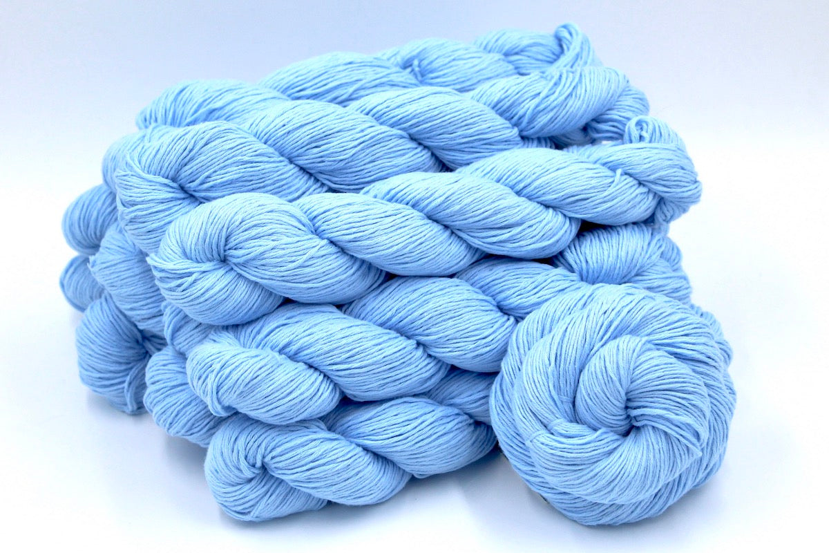 Several skeins of baby blue recycled by hand from unwanted sweaters stacked on top of each other attractively