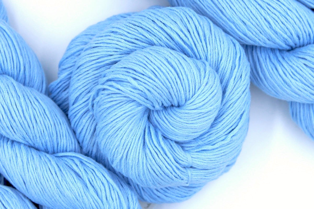 A skein of baby blue Yarn recycled by hand from unwanted sweaters swirled attractively in the center of the frame