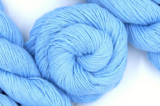 A skein of baby blue Yarn recycled by hand from unwanted sweaters swirled attractively in the center of the frame