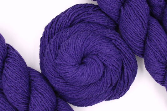 A skein of Vegan, Purple, 62% Cotton, 38% Acrylic, DK weight Yarn recycled by hand from unwanted sweaters swirled attractively in the center of the frame.