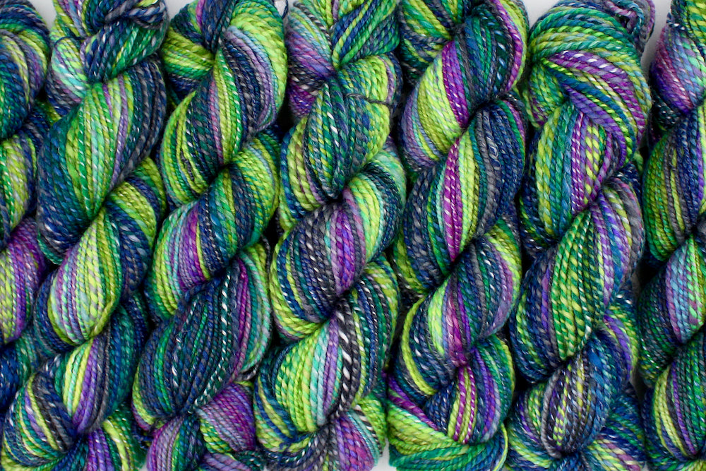 Six one of a kind, Worsted weight, hand dyed Gradient skein of multicolored Navy Blue, Forest Green, Lime Green, Baby Blue, Purple, and Magenta, Ombre self-striping Wool, Bamboo, and Silk Yarn lined up side by side.