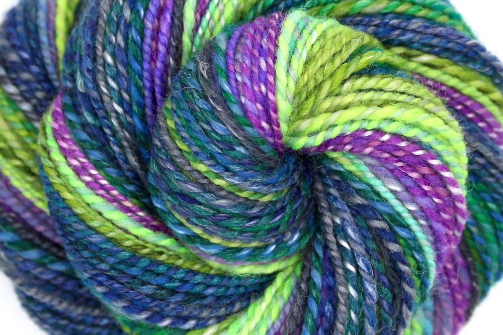 A close up view of a one of a kind, Worsted weight, hand dyed Gradient skein of multicolored Navy Blue, Forest Green, Lime Green, Baby Blue, Purple, and Magenta, Ombre self-striping Wool, Bamboo, and Silk Yarn.