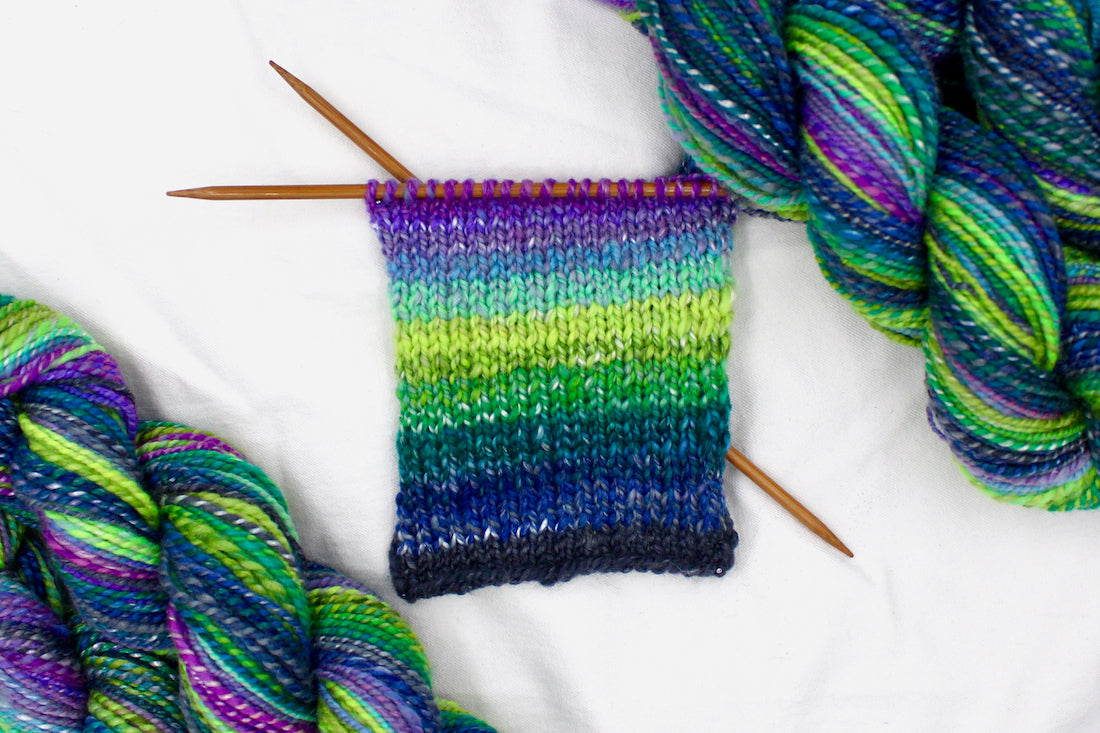 A sample swatch knitted on size 5 knitting needles from a one of a kind, Worsted weight, hand dyed Gradient skein of multicolored Navy Blue, Forest Green, Lime Green, Baby Blue, Purple, and Magenta, Ombre self-striping Wool, Bamboo, and Silk Yarn.