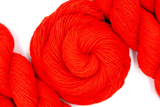 A skein of Bright Orange, Fingering weight Yarn recycled by hand from unwanted sweaters swirled attractively in the center of the frame.