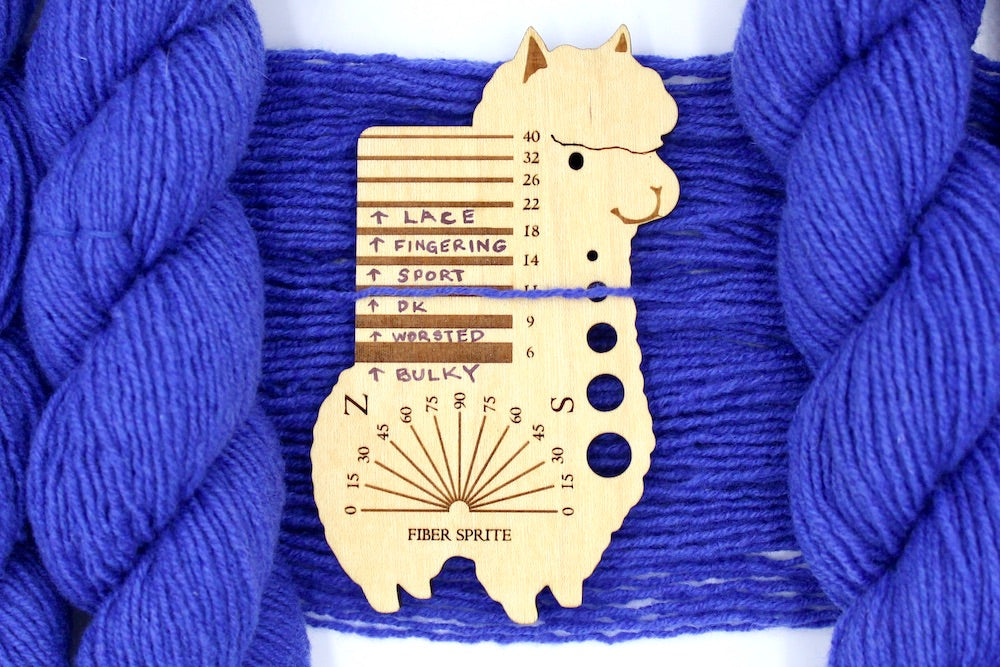 A skein of Violet, Dk weight Yarn recycled by hand from unwanted sweaters draped over a Llama shaped Yarn weight tool.