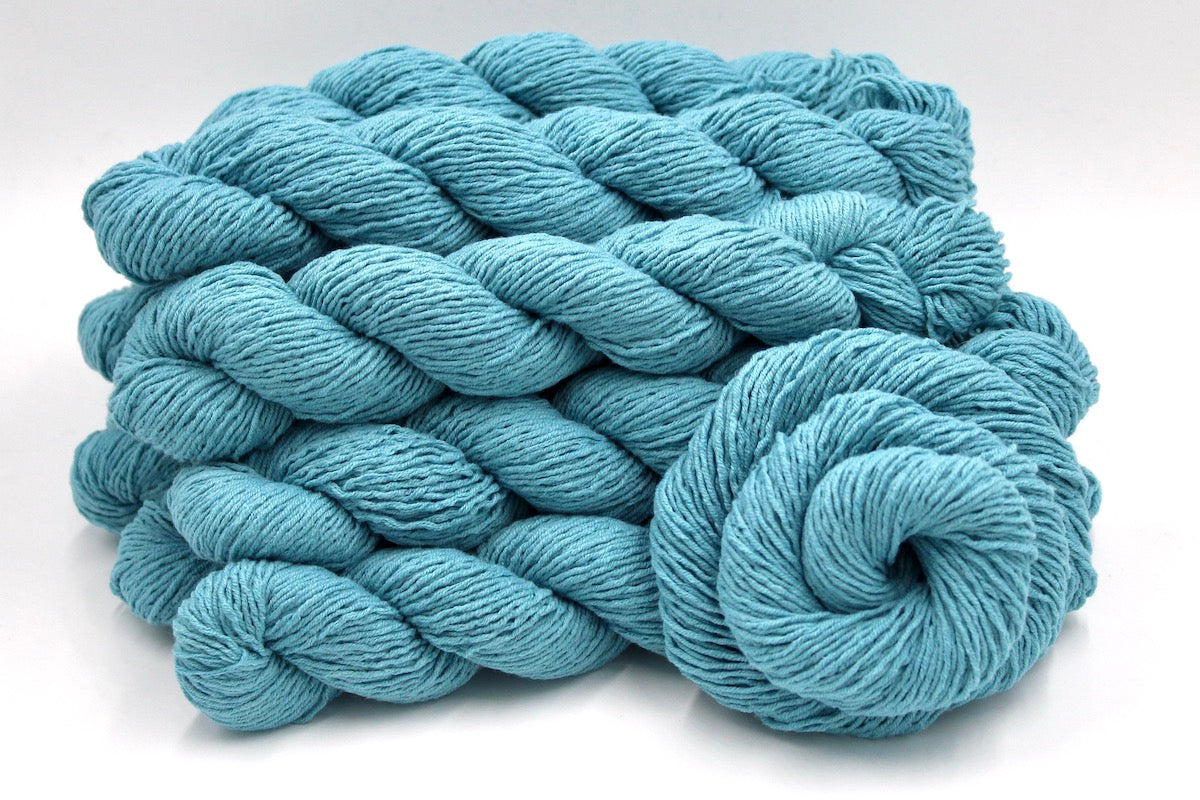 Several skeins of Light Blue, DK weight recycled by hand from unwanted sweaters stacked on top of each other attractively.