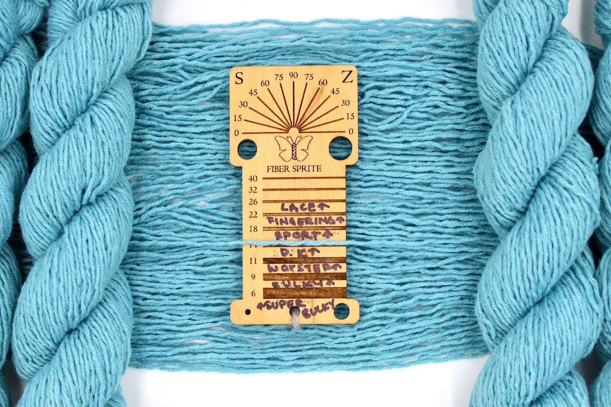 A skein of Light Blue, Dk weight Yarn recycled by hand from unwanted sweaters draped over a Llama shaped Yarn weight tool.