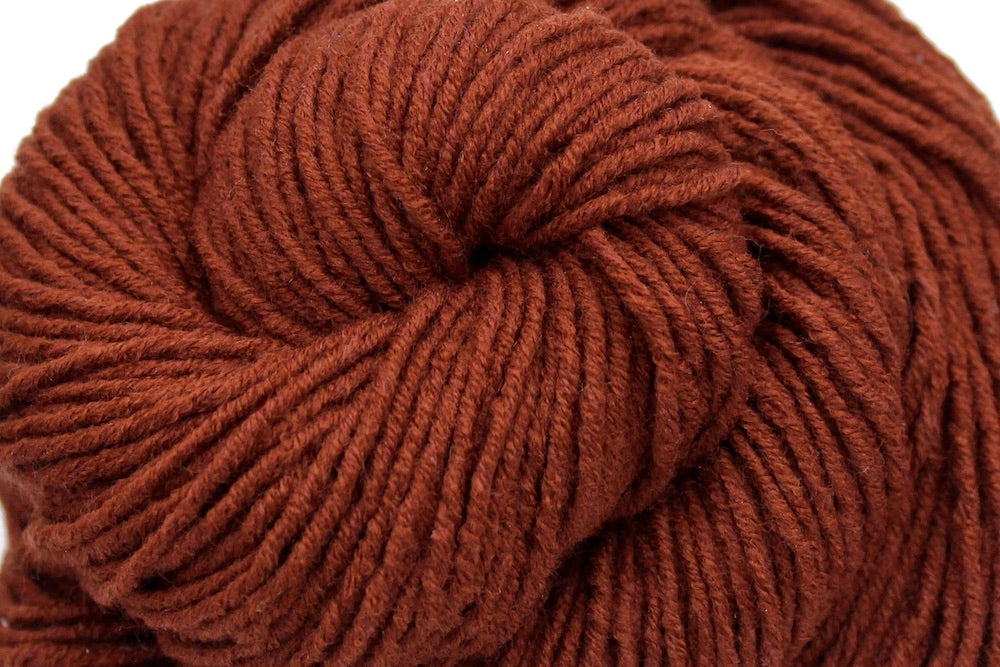 A close up shot of a skein of Reddish brown, Worsted weight Yarn recycled by hand from unwanted sweaters beautifully coiled in the center of the frame.