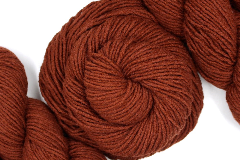 A skein of Reddish brown, Worsted weight Yarn recycled by hand from unwanted sweaters swirled attractively in the center of the frame.