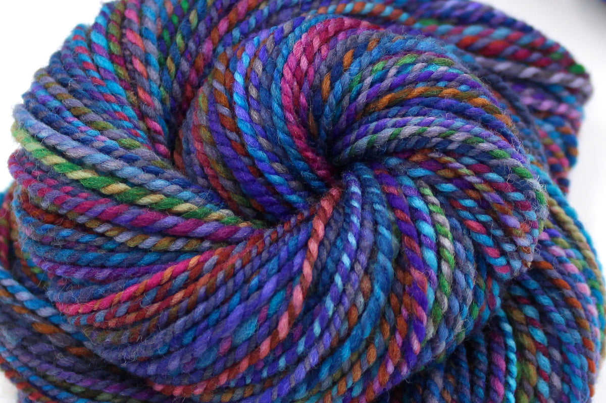 A close up view of a one of a kind, hand dyed Variegated skein of multicolored Rainbow self-striping wool Yarn.