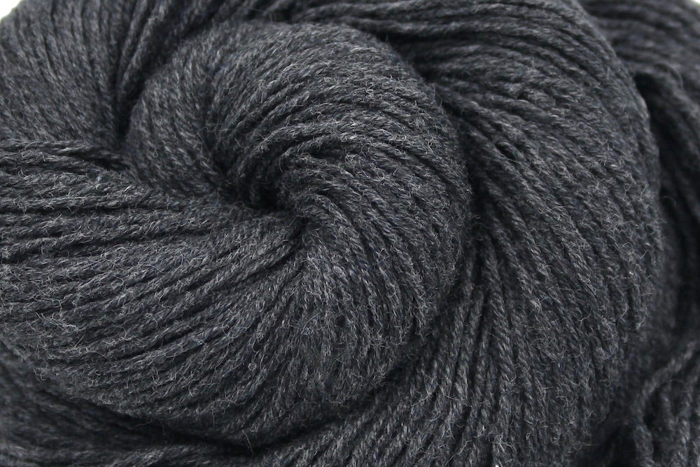 A close up shot of a skein of Dark Grey, Fingering weight Yarn recycled by hand from unwanted sweaters beautifully coiled in the center of the frame.