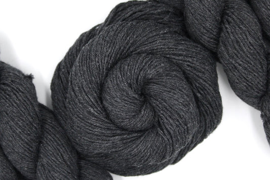 A skein of Dark Grey, Fingering weight Yarn recycled by hand from unwanted sweaters swirled attractively in the center of the frame.