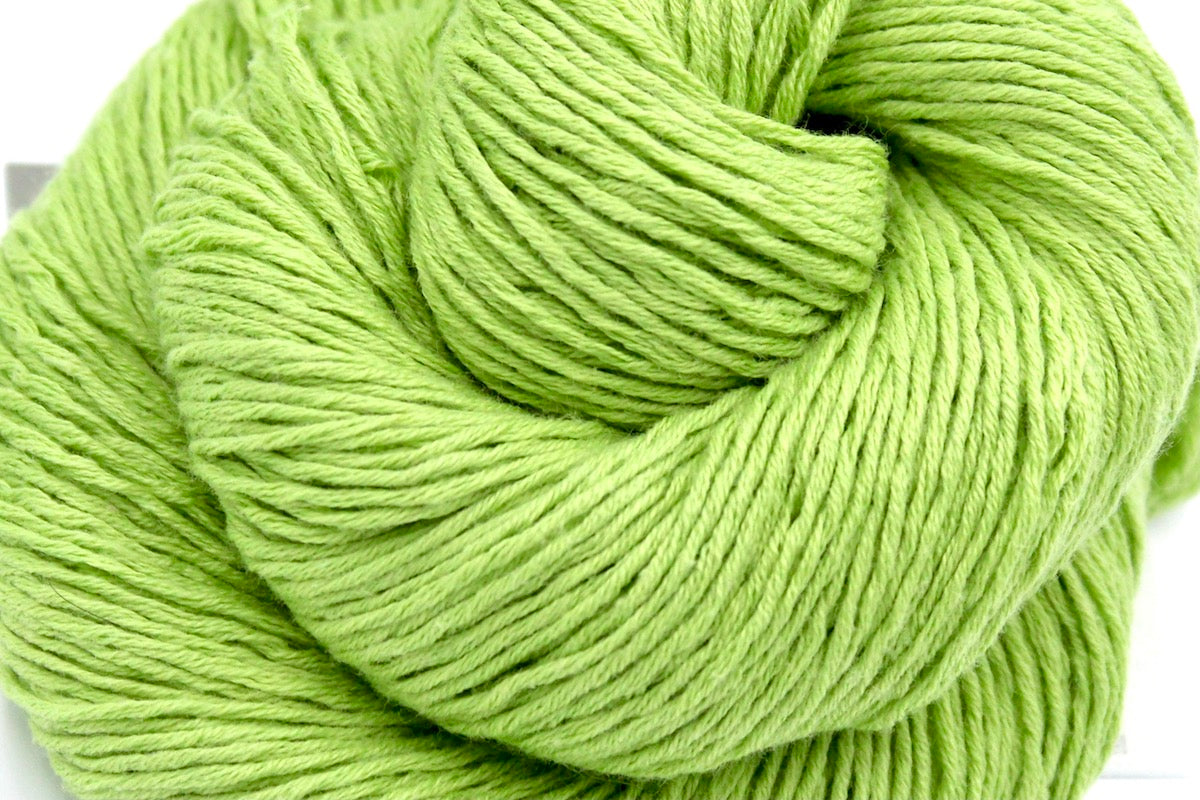 A close up shot of a skein of Lime Green, Fingering weight Yarn recycled by hand from unwanted sweaters beautifully coiled in the center of the frame.