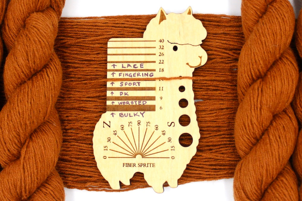 A skein of Brownish Orange, Sport Yarn recycled by hand from unwanted sweaters draped over a Llama shaped Yarn weight tool.