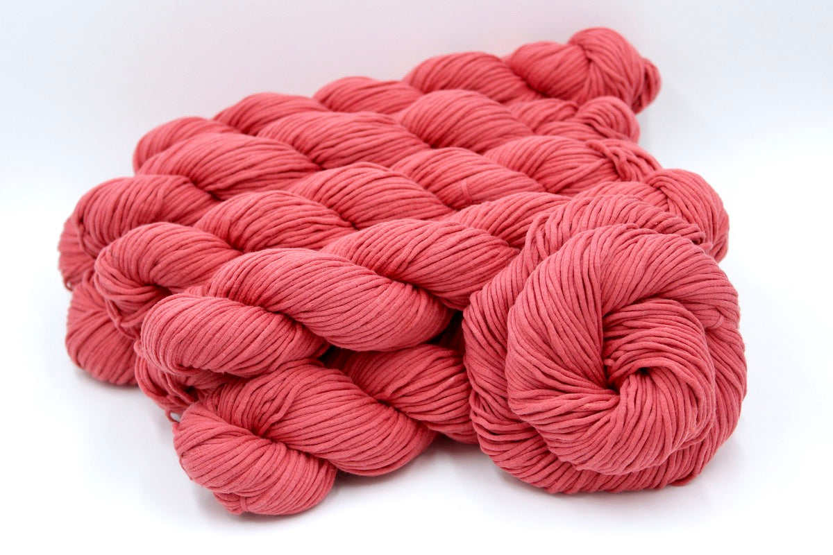 Several skeins of Coral Pink, Worsted weight recycled by hand from unwanted sweaters stacked on top of each other attractively.