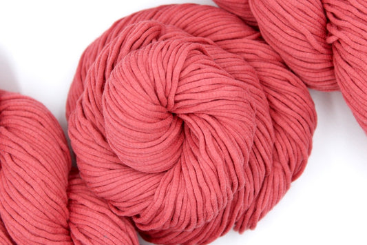 A skein of Coral Pink, Worsted weight Yarn recycled by hand from unwanted sweaters swirled attractively in the center of the frame.