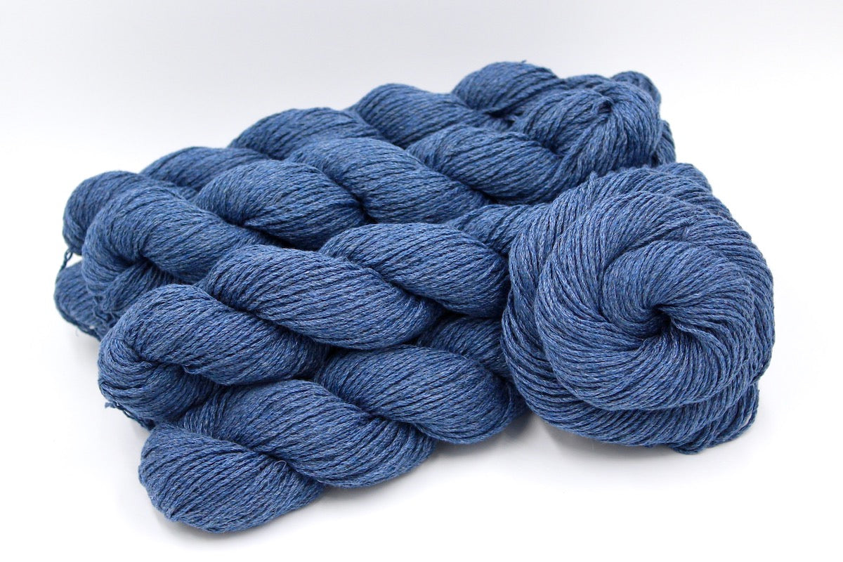 Several skeins of Cornflower Blue, Dk weight recycled by hand from unwanted sweaters stacked on top of each other attractively.