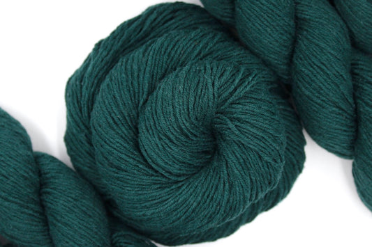 A skein of Dark Forest green, Fingering weight Yarn recycled by hand from unwanted sweaters swirled attractively in the center of the frame.