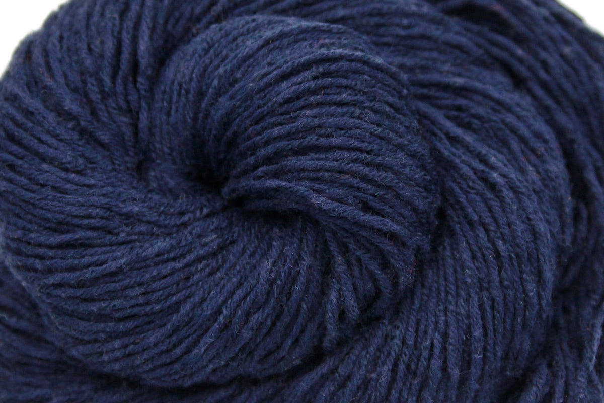 A close up shot of a skein of Dark Navy Blue, Fingering weight Yarn recycled by hand from unwanted sweaters beautifully coiled in the center of the frame.
