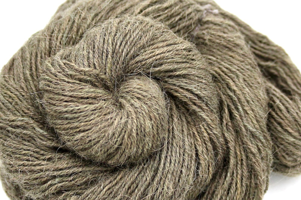 A close up shot of a skein of Natural Alpaca, Fingering weight Yarn recycled by hand from unwanted sweaters beautifully coiled in the center of the frame.