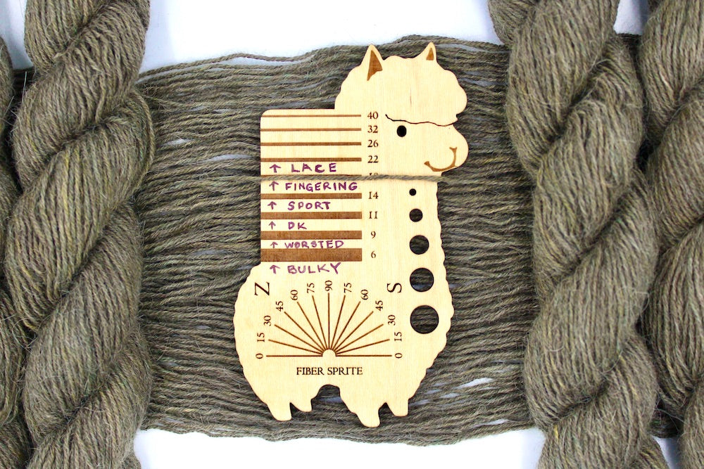 A skein of Natural Alpaca, Fingering Yarn recycled by hand from unwanted sweaters draped over a Llama shaped Yarn weight tool.