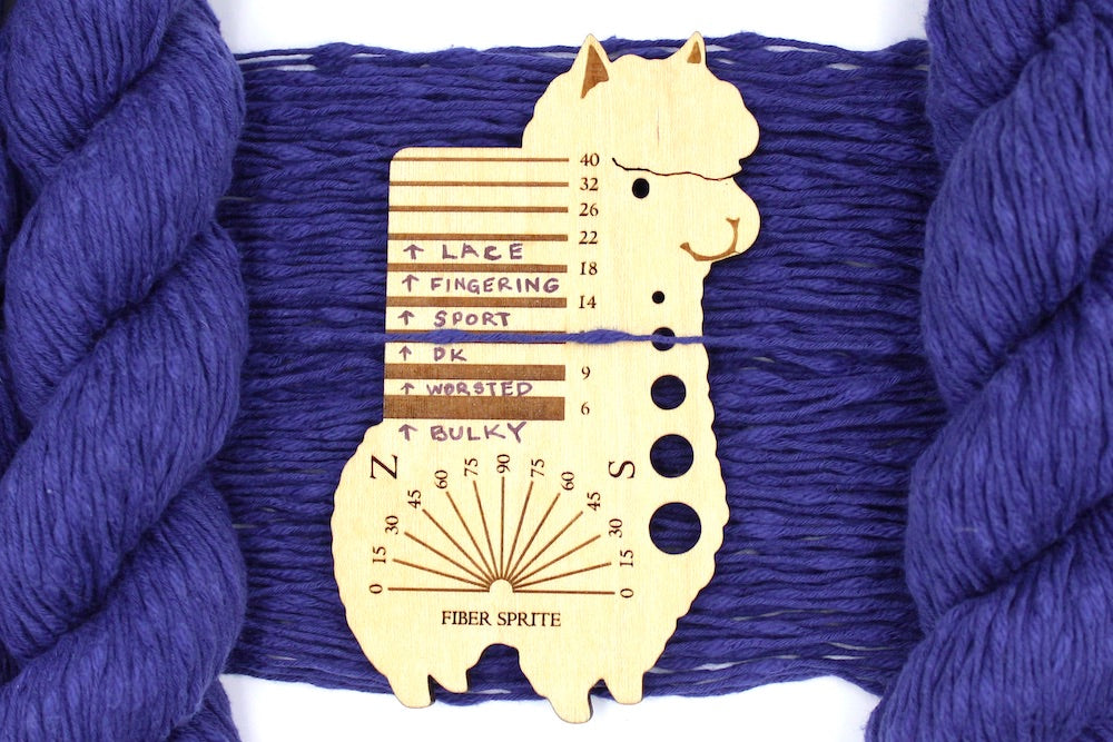 A skein of Deep Violet, Cotton Boucle, Dk Weight Yarn recycled by hand from unwanted sweaters draped over a Llama shaped Yarn weight tool.
