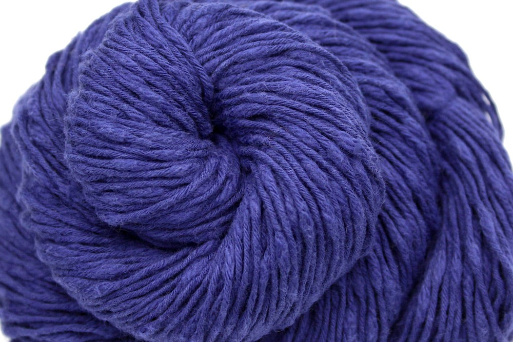 A close up shot of a skein of Deep Violet, Cotton Boucle, Dk weight Yarn recycled by hand from unwanted sweaters beautifully coiled in the center of the frame.
