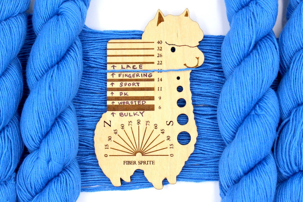 A skein of Baby Blue, Cotton Rayon Nylon, Fingering Weight Yarn recycled by hand from unwanted sweaters draped over a Llama shaped Yarn weight tool.