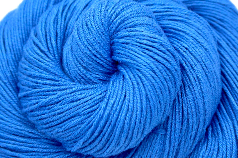 A close up shot of a skein of Baby Blue, Cotton Rayon Nylon, Fingering weight Yarn recycled by hand from unwanted sweaters beautifully coiled in the center of the frame.