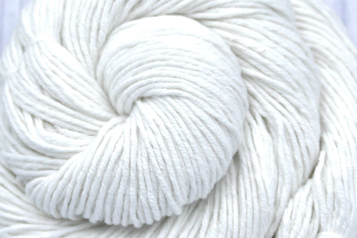 A close up shot of a skein of Pure White, Cotton, Fingering weight Yarn recycled by hand from unwanted sweaters beautifully coiled in the center of the frame.