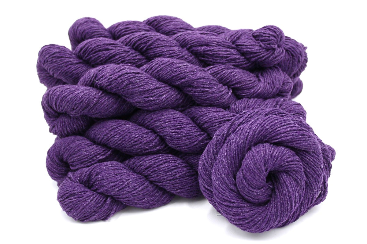 Several skeins of Eggplant Purple, Cotton, Acrylic, Dk weight recycled by hand from unwanted sweaters stacked on top of each other attractively.