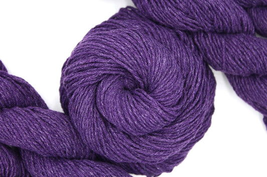 A skein of Eggplant Purple, Cotton, Acrylic, Dk weight Yarn recycled by hand from unwanted sweaters swirled attractively in the center of the frame.