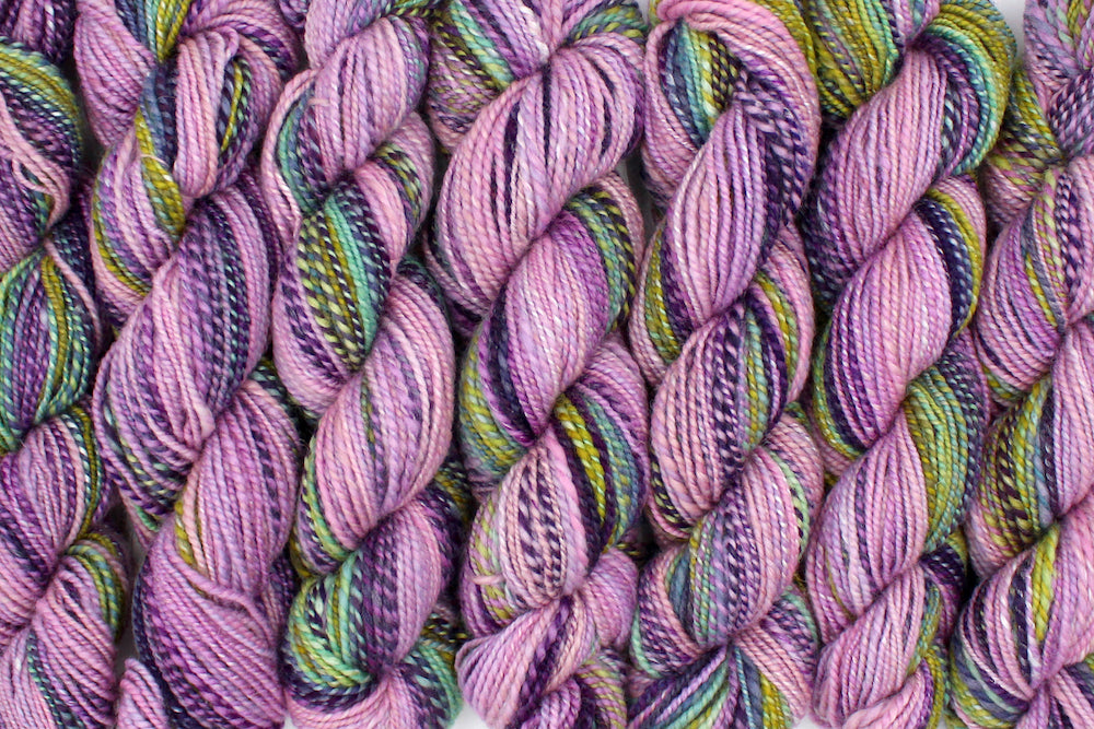 Six one of a kind, Dk weight, hand dyed Gradient skein of multicolored Ballerina Pink, then move through Lavender, Magenta, Deep Purple, Baby Blue, Seafoam, and then finishes with Lime Green, Ombre self-striping Wool, and Mulberry Silk Yarn lined up side by side