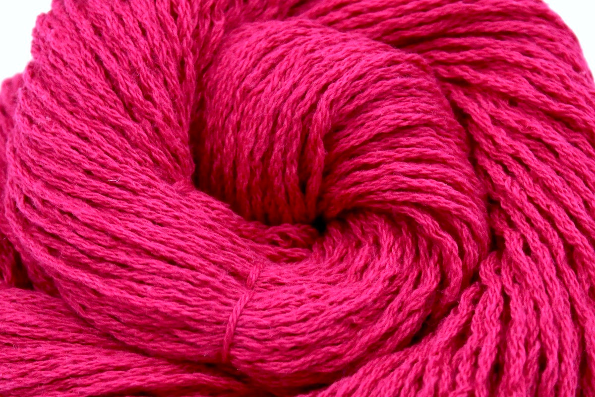 A close up shot of a skein of Hot Pink Fuchsia, Cotton/ Nylon/ Wool/ Polyester, Worsted weight Yarn recycled by hand from unwanted sweaters beautifully coiled in the center of the frame.