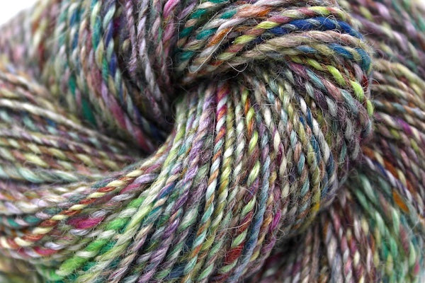 A close up view of a one of a kind, hand dyed variegated skein of multicolored Navy, Maroon, Fuchsia, Teal, Kelly Green, Lime Green, and Gold self-striping wool Yarn.