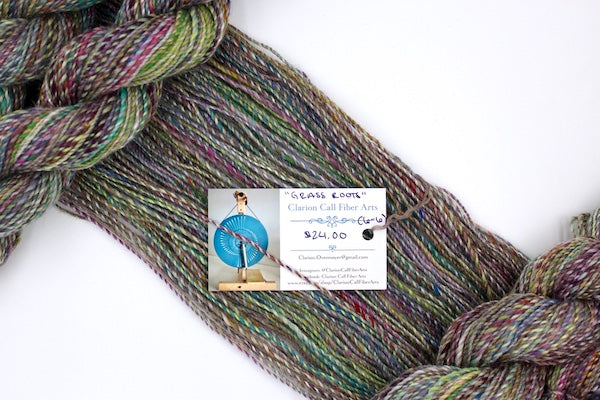 A one of a kind, hand dyed variegated skein of multicolored Navy, Maroon, Fuchsia, Teal, Kelly Green, Lime Green, and Gold self-striping wool Yarn draped diagonally across the frame, so you can really see the color play.