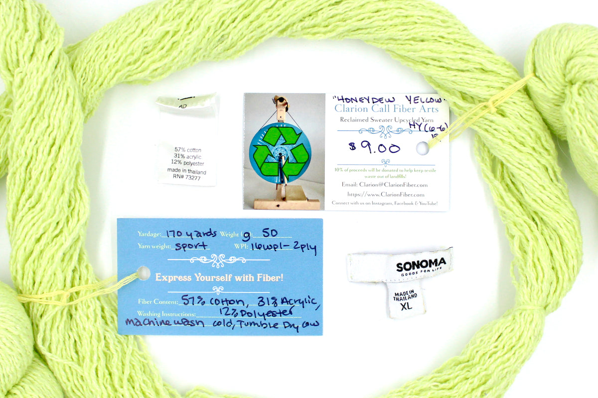 A skein of Vegan, Neon Greenish Yellow, Cotton, Acrylic, Polyester, Sport Weight yarn encircling the sweater labels it was recycled from, as well as the hand written yarn tags detailing the specs of this recycled yarn to help you make your next project!