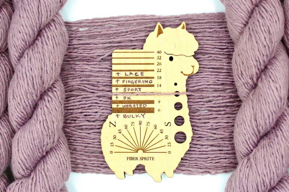 A skein of Dusky Mauve, Acrylic, Nylon, Wool, Mohair, Dk Weight Yarn recycled by hand from unwanted sweaters draped over a Llama shaped Yarn weight tool.