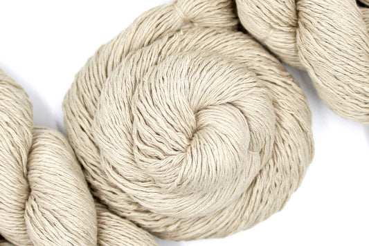 A skein of Vegan, Tan/ Beige/ Cream, Acrylic/ Cotton/ Nylon, Sport weight Yarn recycled by hand from unwanted sweaters swirled attractively in the center of the frame.