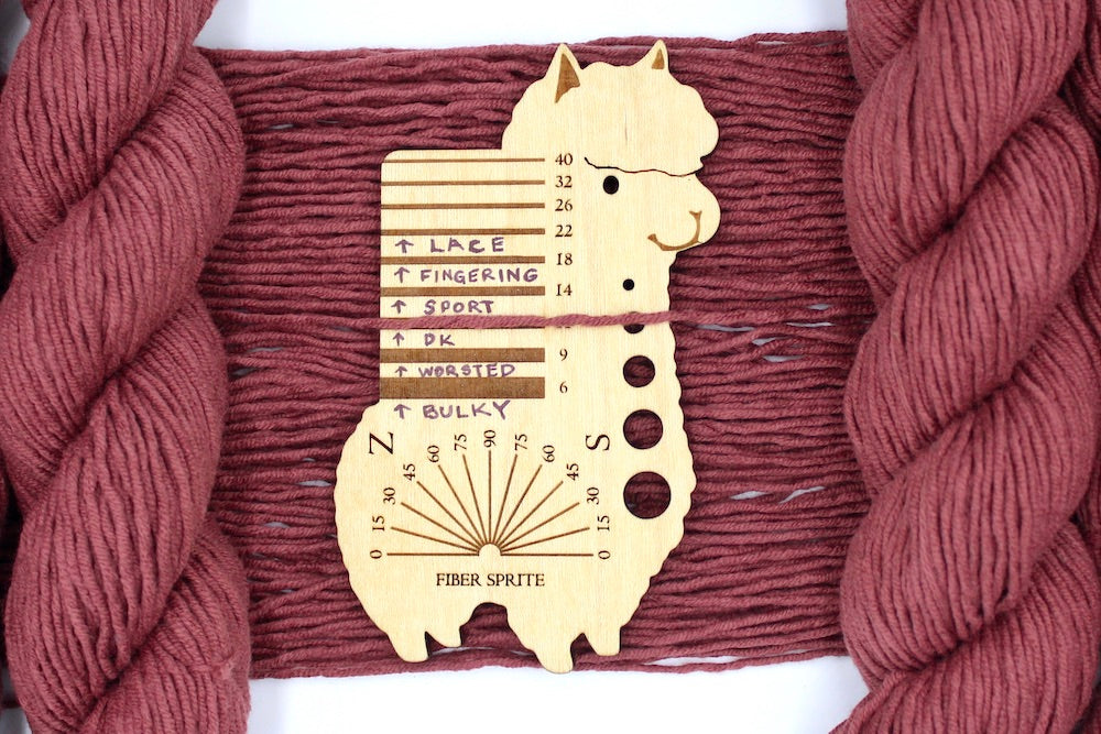 A skein of Vegan, Light Reddish Brown, Cotton/ Acrylic, Dk Weight Yarn recycled by hand from unwanted sweaters draped over a Llama shaped Yarn weight tool.