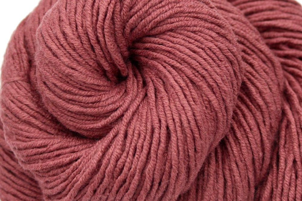 A close up shot of a skein of Light Reddish Brown, Cotton/ Acrylic, Dk weight Yarn recycled by hand from unwanted sweaters beautifully coiled in the center of the frame.