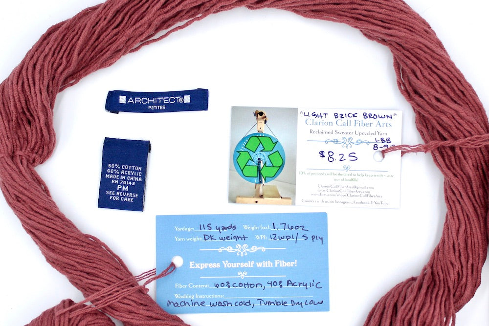 A skein of Vegan, Light Reddish Brown, Cotton/ Acrylic, Dk Weight yarn encircling the sweater labels it was recycled from, as well as the hand written yarn tags detailing the specs of this upcycled yarn to help you make your next project!