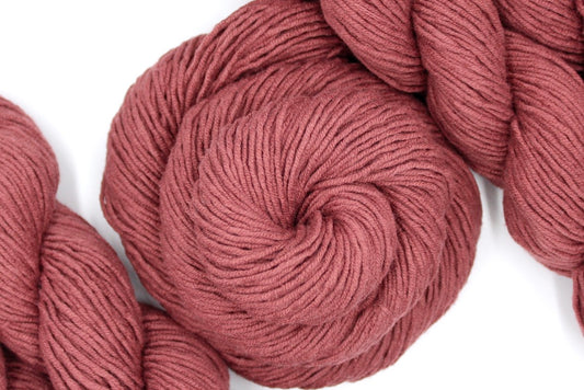 A skein of Vegan, Light Reddish Brown, Cotton/ Acrylic, Dk weight Yarn recycled by hand from unwanted sweaters swirled attractively in the center of the frame.