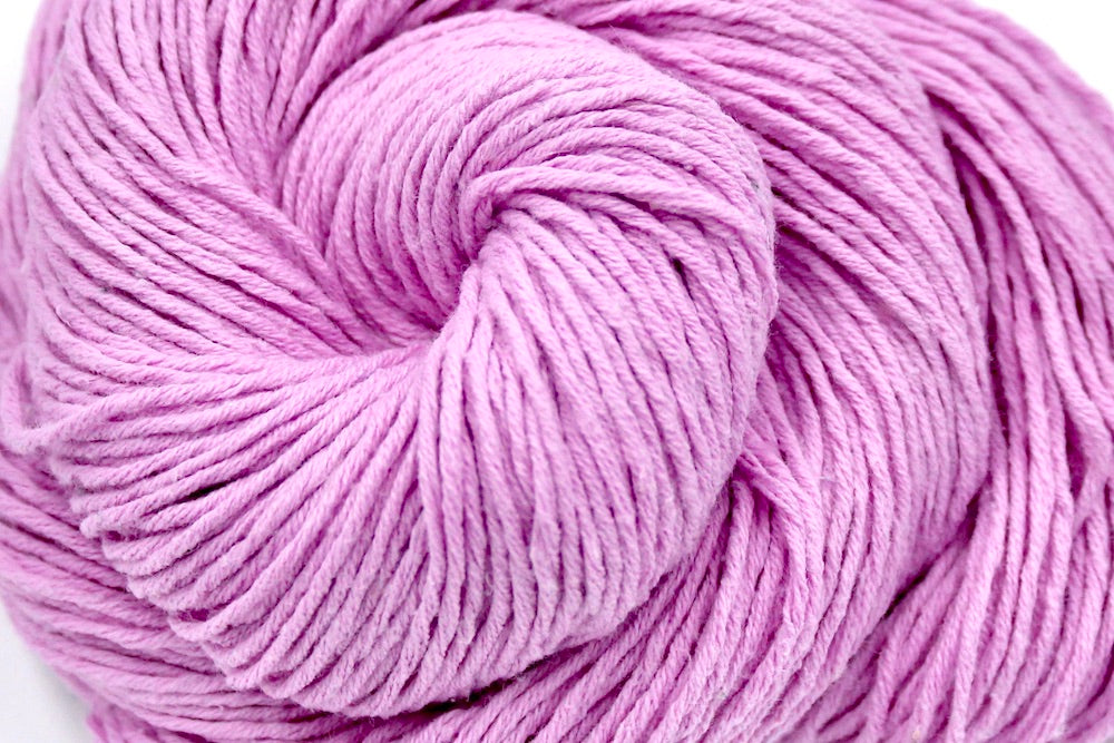 A close up shot of a skein of Vegan, Pastel Pink, 100% Cotton, Sport weight Yarn recycled by hand from unwanted sweaters beautifully coiled in the center of the frame.
