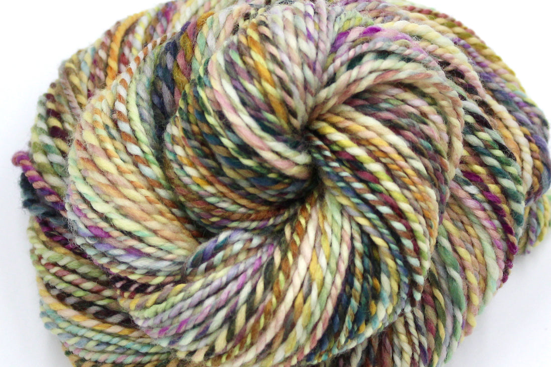 A close up view of a one of a kind, Worsted Weight, hand dyed variegated skein of multicolored Green, Maroon, Pink, Yellow and Chartreuse, self-striping superwash wool Yarn.