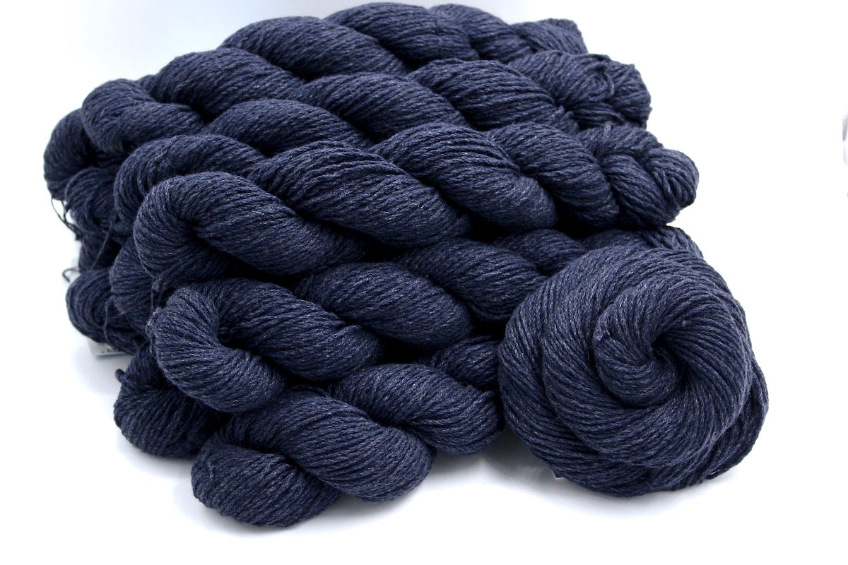 Several skeins of Vegan, Slate Navy Blue, Cotton/ Acrylic, Dk weight recycled by hand from unwanted sweaters stacked on top of each other attractively.