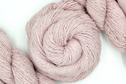 A skein of Vegan, Light Pastel Pink, Cotton/ Acrylic/ Polyester, Dk weight Yarn recycled by hand from unwanted sweaters swirled attractively in the center of the frame.
