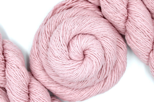 A skein of Vegan, Light Ballet Pink, Cotton/ Acrylic, Sport weight Yarn recycled by hand from unwanted sweaters swirled attractively in the center of the frame.